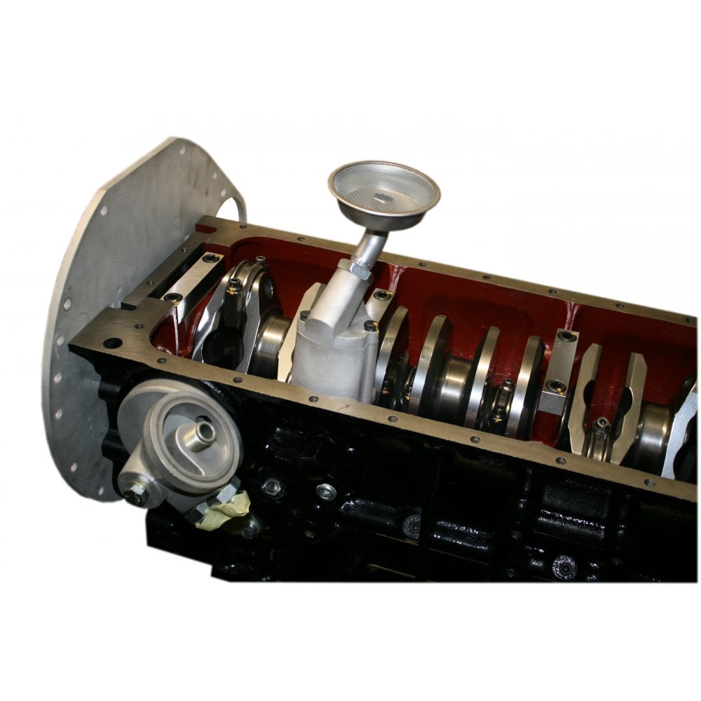 A close-up view of a TR5-6 engine block reveals the crankshaft and internal components, featuring the Racetorations Track Day/Competition Oil Pump Complete Kit with its metal oil pick-up tube visible.