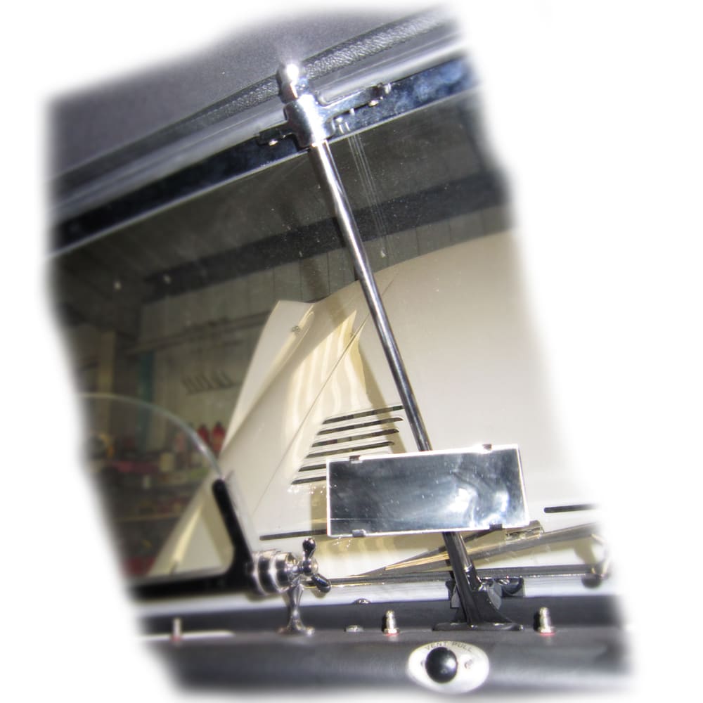 Close-up of a Racetorations Windscreen Top Rail Brace for TR2-3A, featuring the central support rod, a compact rear-view mirror, and a glimpse of the open car bonnet in the background.