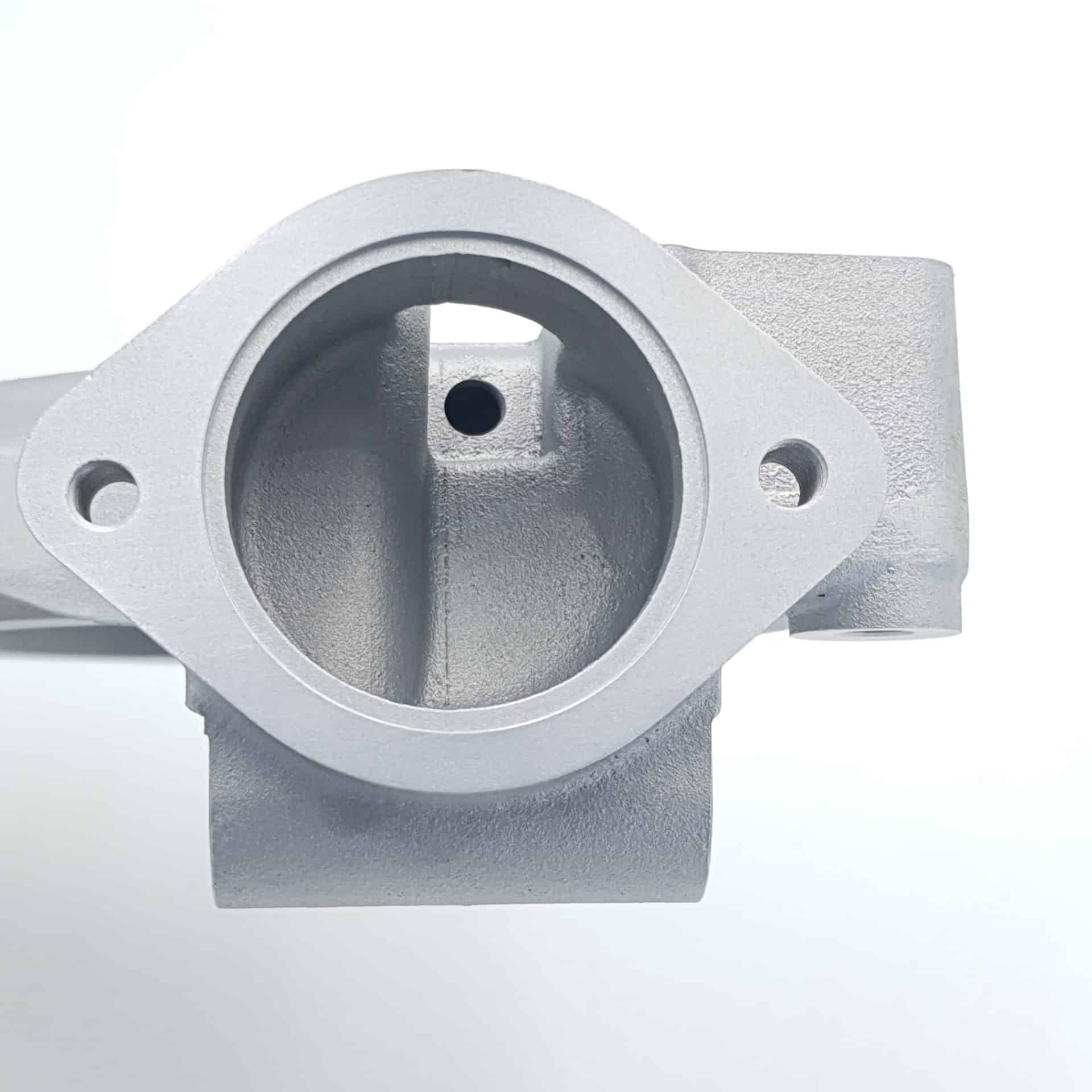 A top view of the Racetorations Aluminium Water Pump Housing for Triumph TR5, TR250 & TR6, showcasing its silver metallic finish, circular opening, and two bolt holes against a white background.