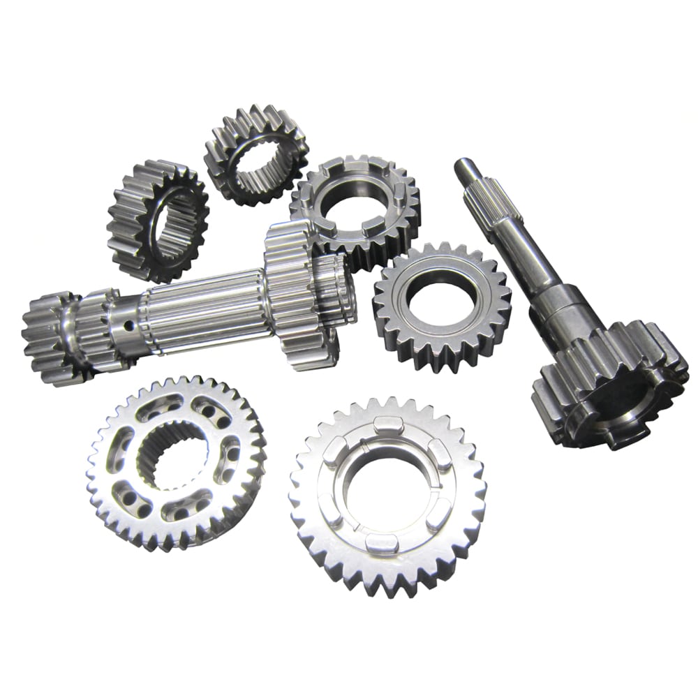 A set of metal gears and shafts on a white background, featuring various sizes and shapes—components from the Racetorations Quaife Competition "Dog" Gearbox for TR2-6.