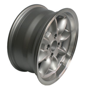 A silver, five-spoke Panasport Alloy Wheel - MGB 15mm Offset with a shiny metallic finish, viewed from an angle that highlights its depth and design, set against a neutral gray background.