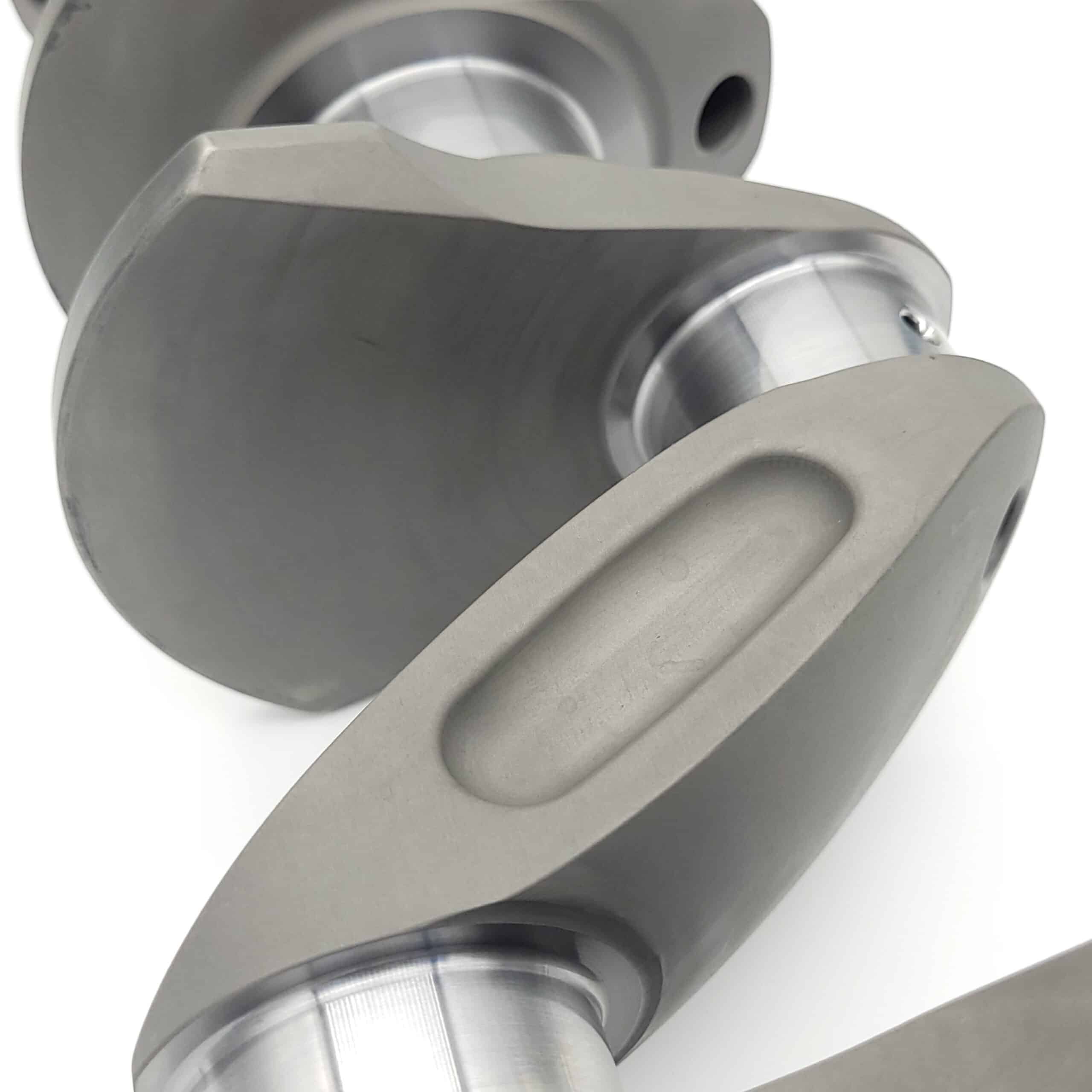 Close-up of the Arrow Precision Engineering Billet Steel Crankshaft, Standard Journal for TR2-4 and Morgan +4, showing its smooth machined surfaces and curved counterweights against a white background.