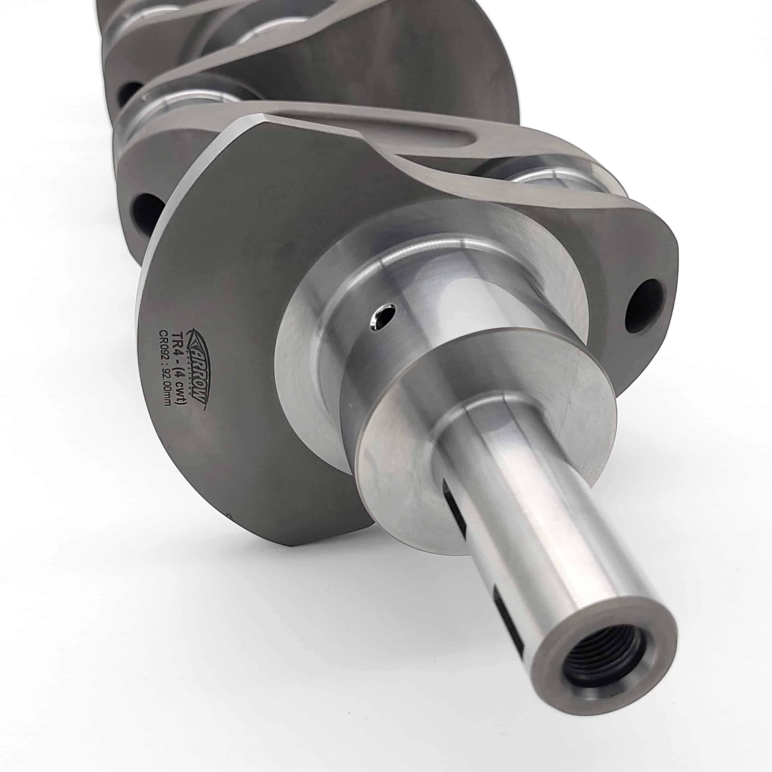 Close-up of the Arrow Precision Engineering Billet Steel Crankshaft, Standard Journal for TR2-4 or Morgan +4, on a white surface, highlighting its smooth finish, detailed machining, and engraved counterweight text.