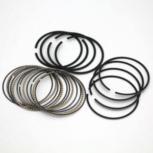 A set of black piston rings, some with metallic linings, arranged in groups on a white background.