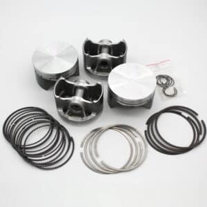 Four metal engine pistons are arranged on a white surface, accompanied by piston rings, circlips, and other small engine components organised in separate groups.