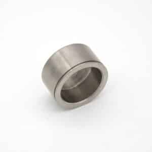 A metallic cylindrical bearing with a hollow centre is placed on a white background. The object has smooth surfaces and appears to be made of stainless steel.