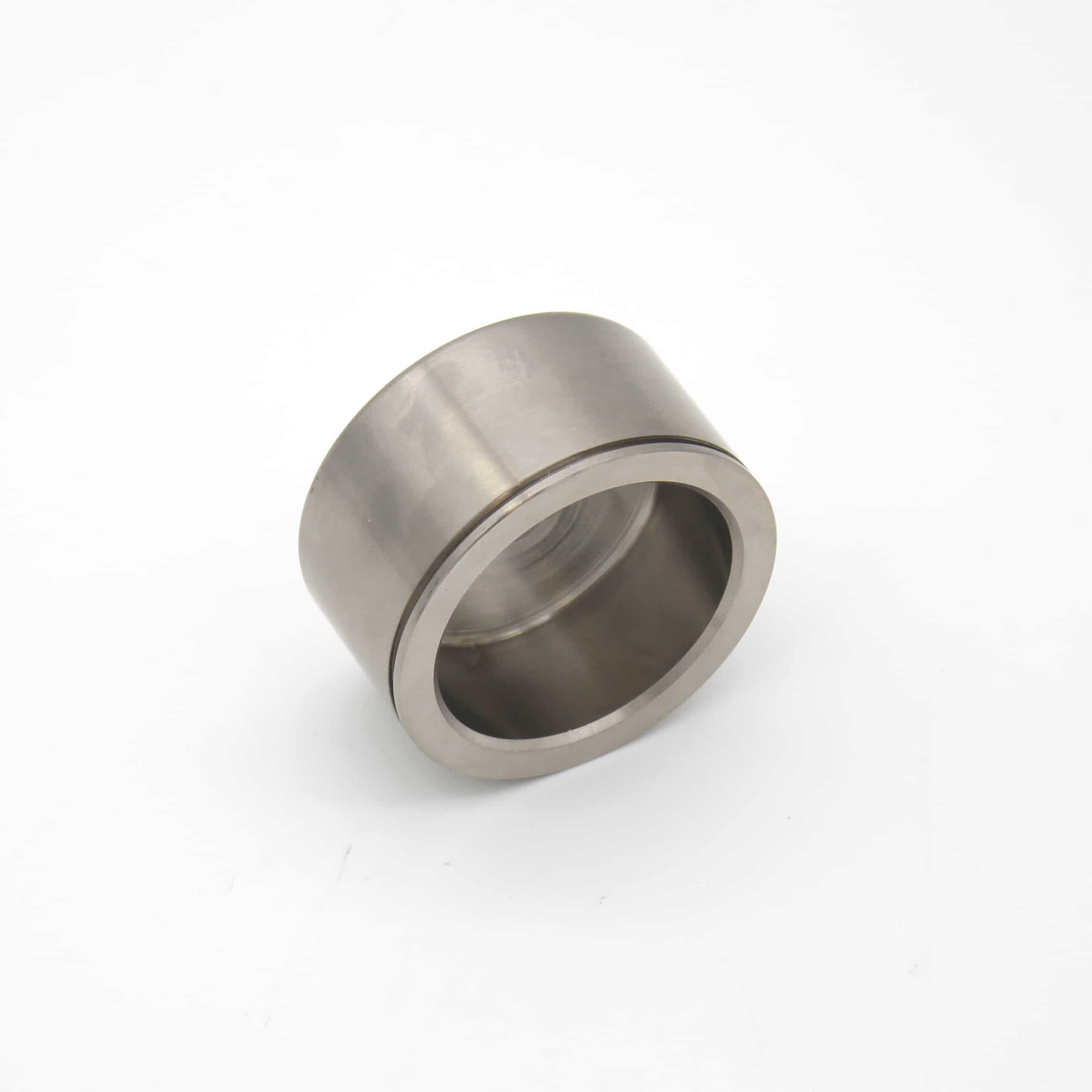 A metallic cylindrical bearing with a hollow centre is placed on a white background. The object has smooth surfaces and appears to be made of stainless steel.