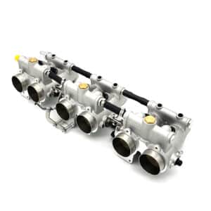A polished aluminium automotive throttle body assembly with four inlet ports, black fuel rail, and gold-coloured caps, isolated on a white background.