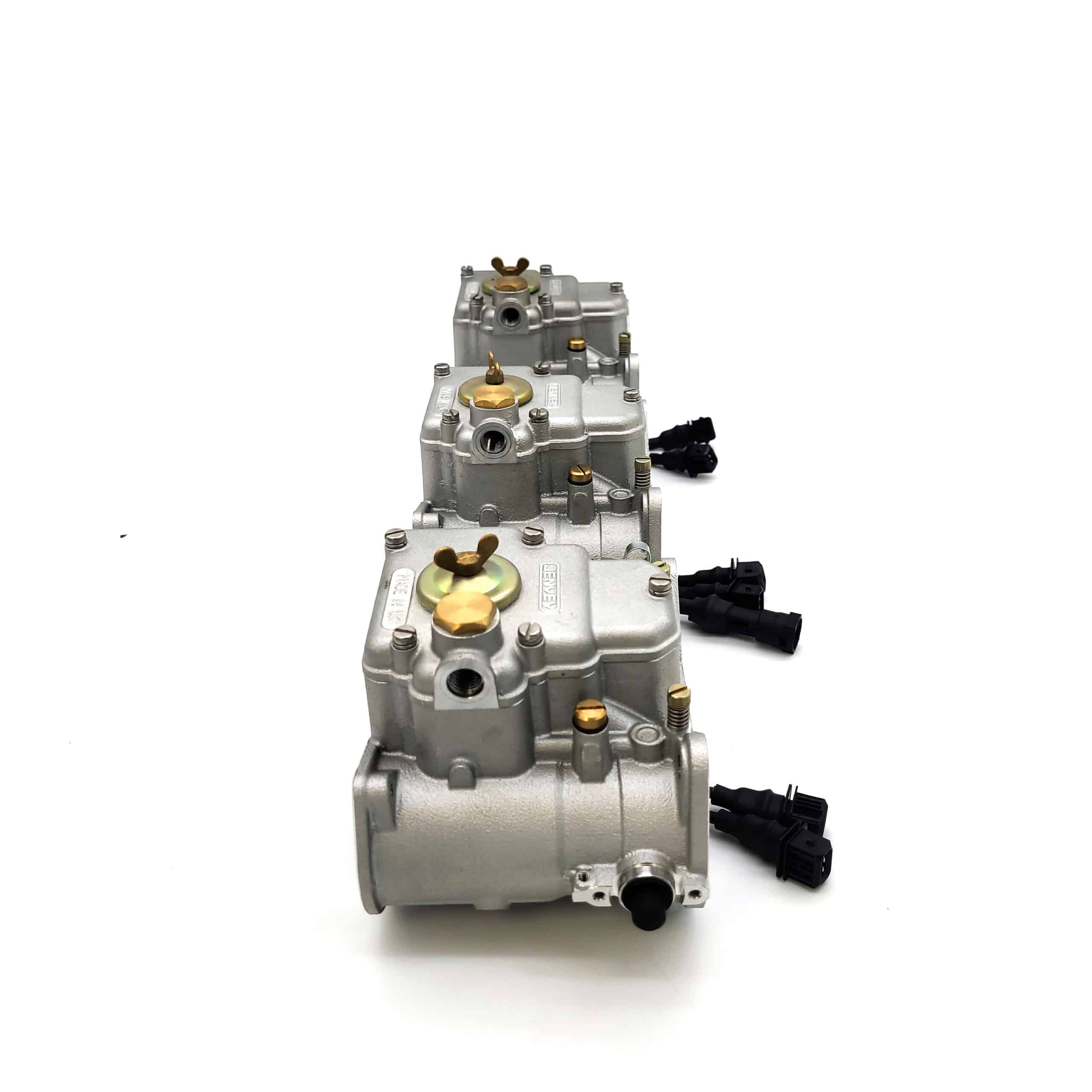Three Jenvey Heritage Throttle Body Sets for TR5-6, featuring silver bodies with black connectors and gold screws, are arranged in a row on a white background.